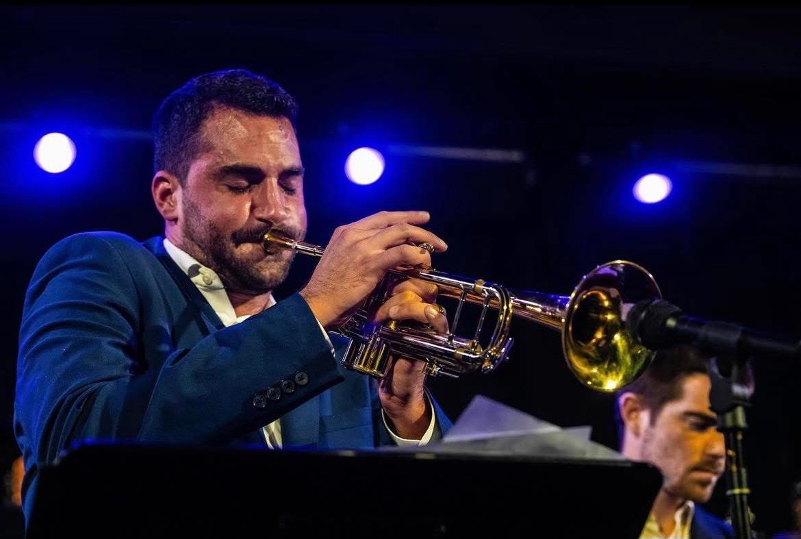 Andrew Wagner playing trumpet under blue stage lights